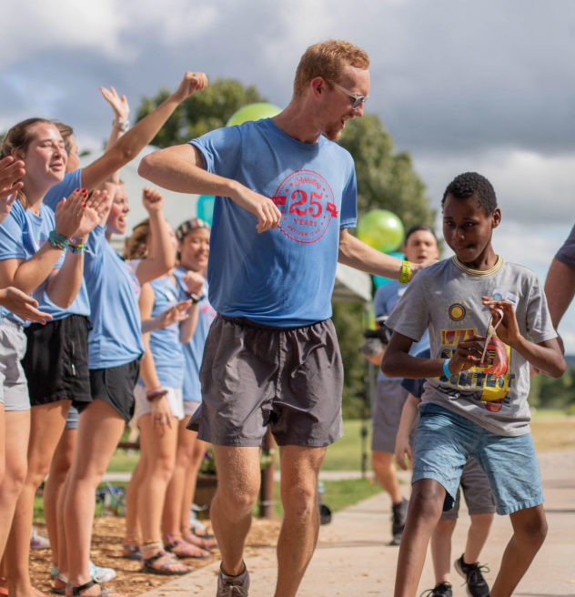 Young male walking down a cheer line with a counselor.