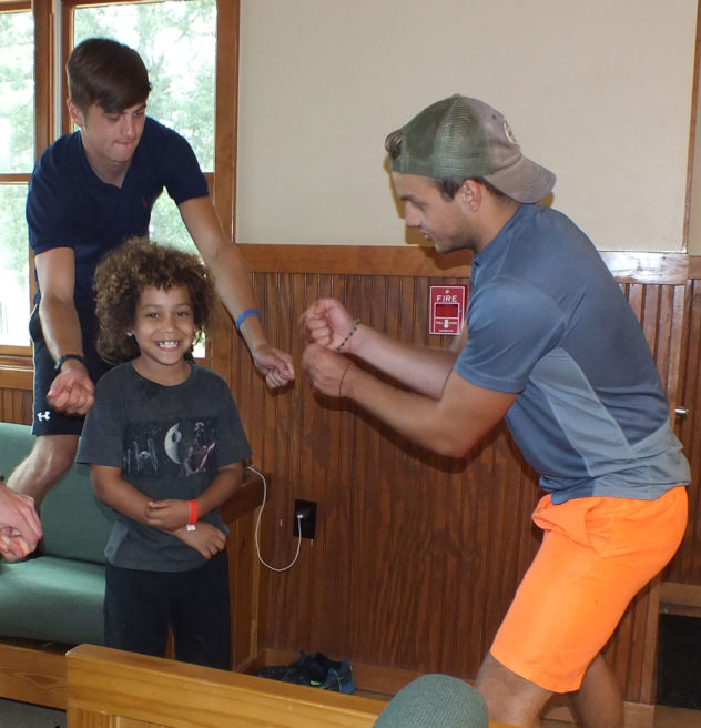 Young boy playing with camp counselors.