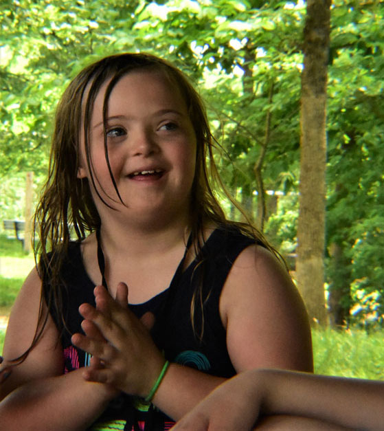 A girl clapping her hands together at camp.