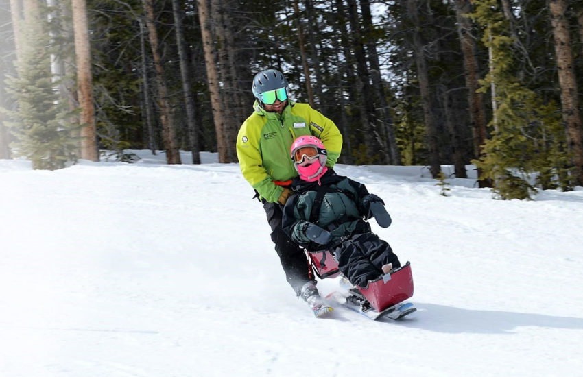 A young girl snow skiing with ski instructor.