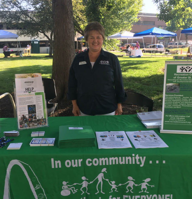 Woman stands at a Recreation Council information table.