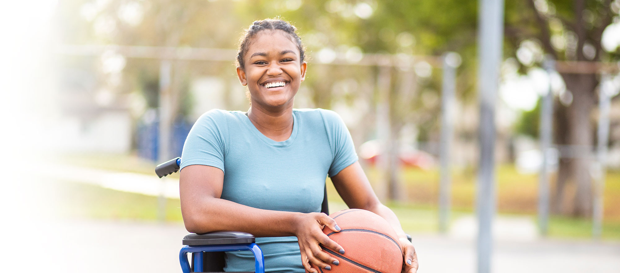 Young girl in wheelchair holding a basketball.