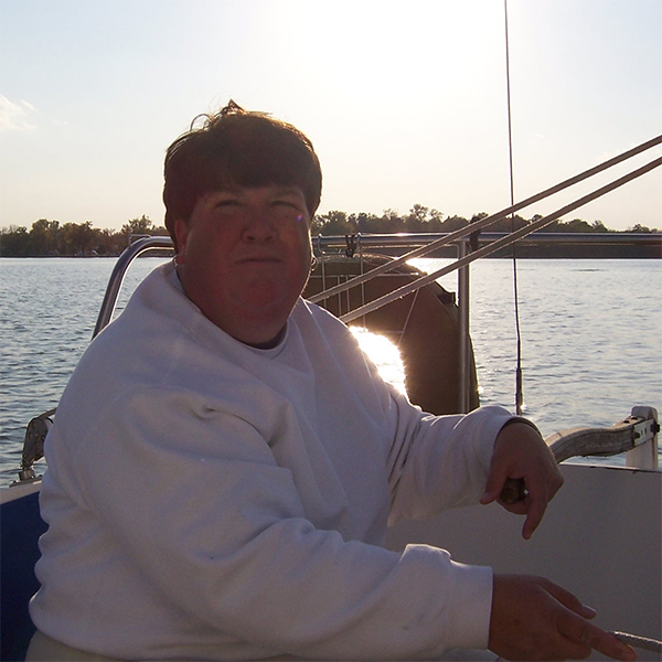 Susan sits in a boat on a lake.