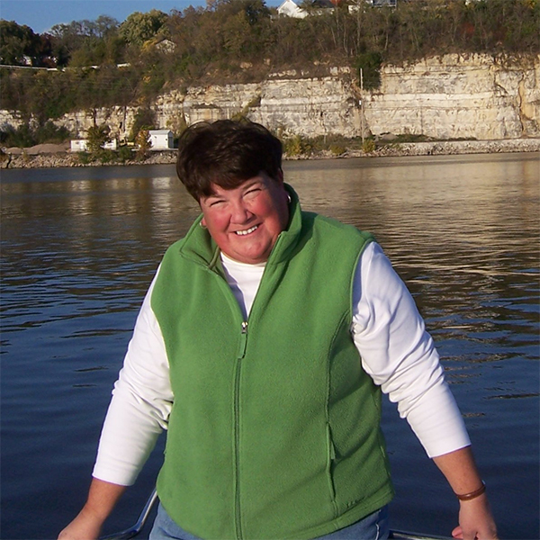 Susan smiles in front of a lake.