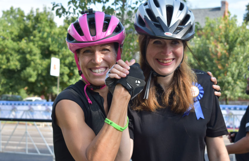 Two women smiling for the camera at a biking event.